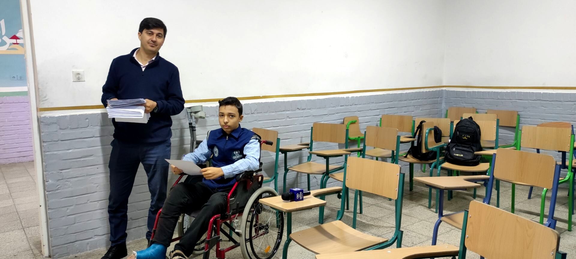 دانش آموز خبرنگار خبرگزاری پانا نشسته بر صندلی چرخدار در پای آزمون نوبت اول